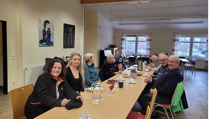 Eine Gruppe an Menschen sitzt gemeinsam an einer Tafel im Mehrgenerationenhaus