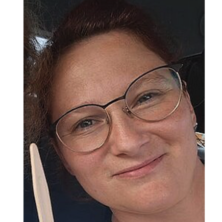 Ein Frau mit Brille lächelt in die Kamera. Es ist nur ihr Gesicht zu sehen. 