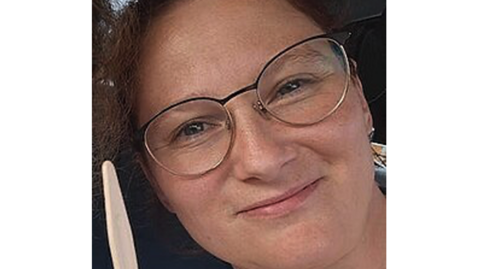 Ein Frau mit Brille lächelt in die Kamera. Es ist nur ihr Gesicht zu sehen. 