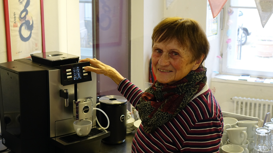 Frau mit braunen Haaren bedient eine Kaffeemaschine