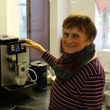 Frau mit braunen Haaren bedient eine Kaffeemaschine