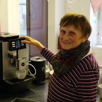 Frau mit braunen Haaren bedient eine Kaffeemaschine