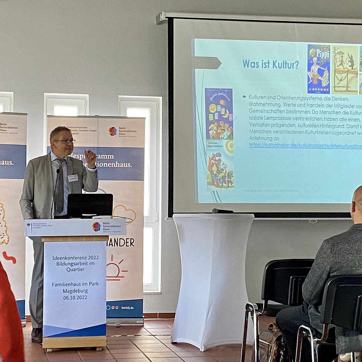 Dr. Winfried Kösters steht an einem Rednerpult vor einer Leinwand mit Präsentation