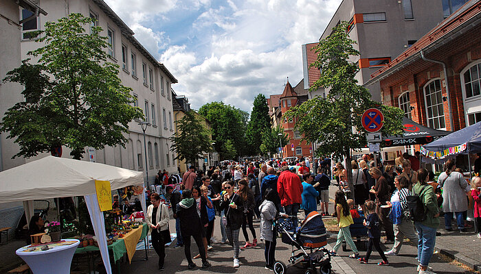 Viele Menschen laufen über ein Straßenfest mit Pavillions und Informationsständen.