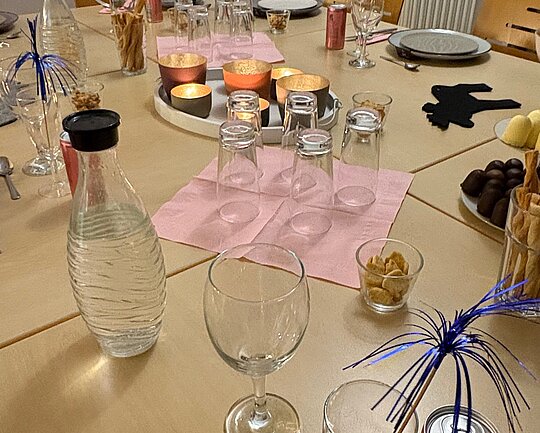 Ein gedeckter Tisch mit Tellern, Gläsern und bunter Dekoration