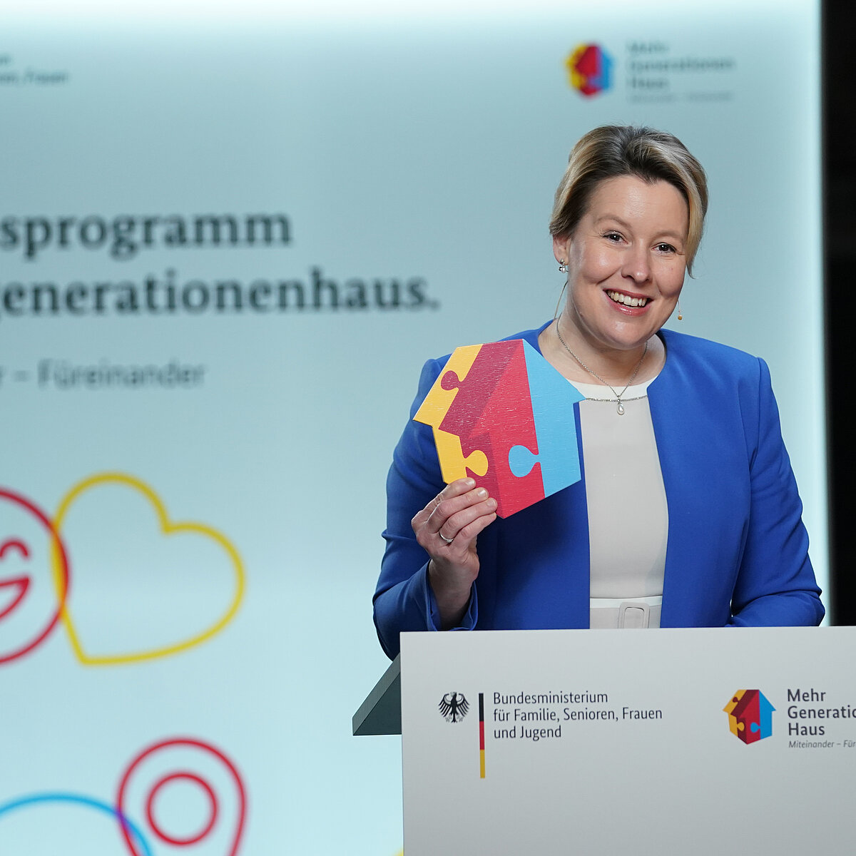 © Jörg Carstensen Bundesfamilienministerin Franziska Giffey steht am Rednerpult mit dem MGH-Häuser-Logo in der Hand