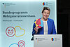 Bundesfamilienministerin Franziska Giffey steht am Rednerpult mit dem MGH-Häuser-Logo in der Hand