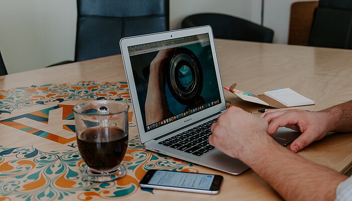 Hände tippen auf der Tastatur eines Laptops.