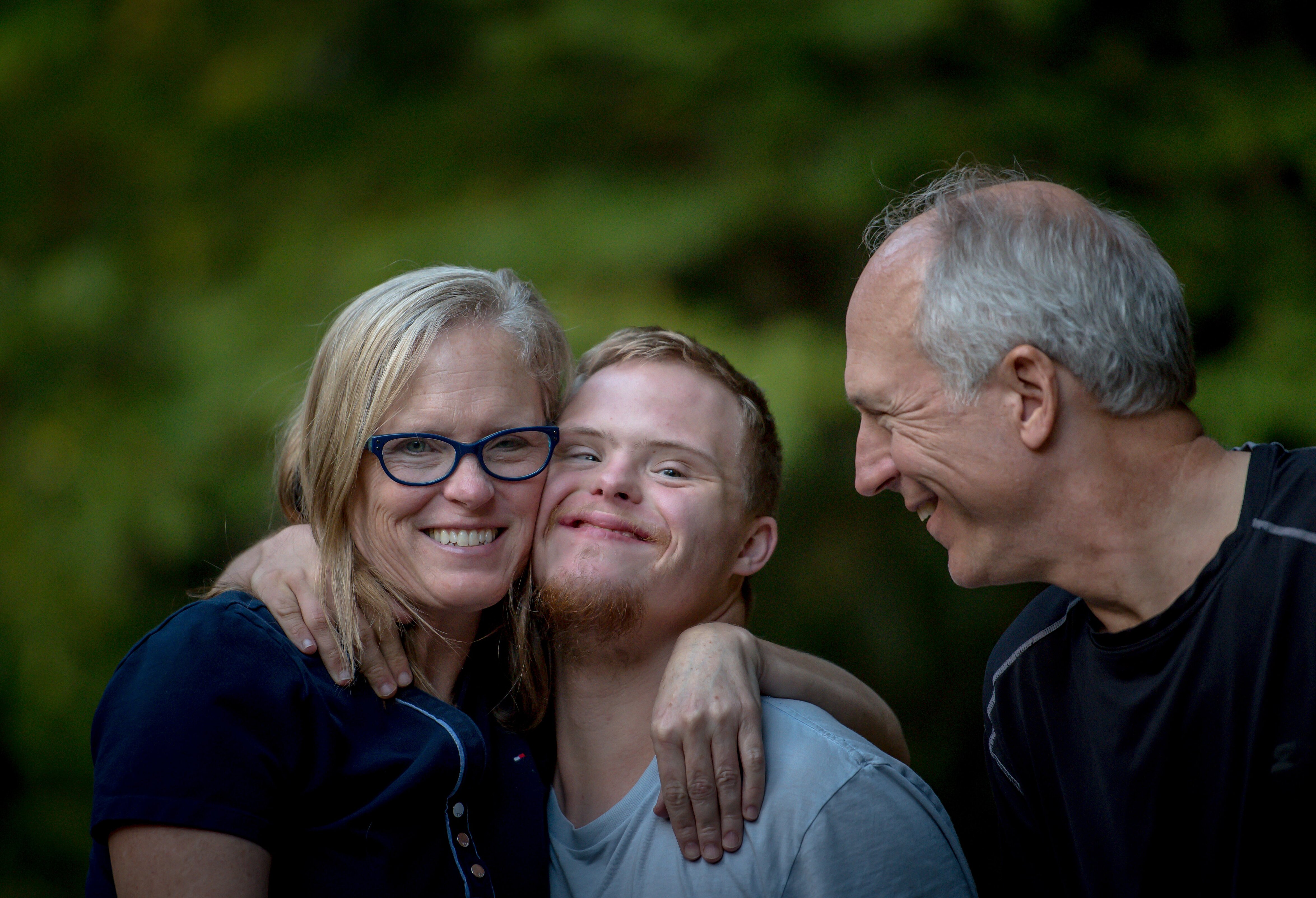 Eine Mutter und ein Vater mit ihrem Sohn in ihrer Mitte, alle drei lächeln. 