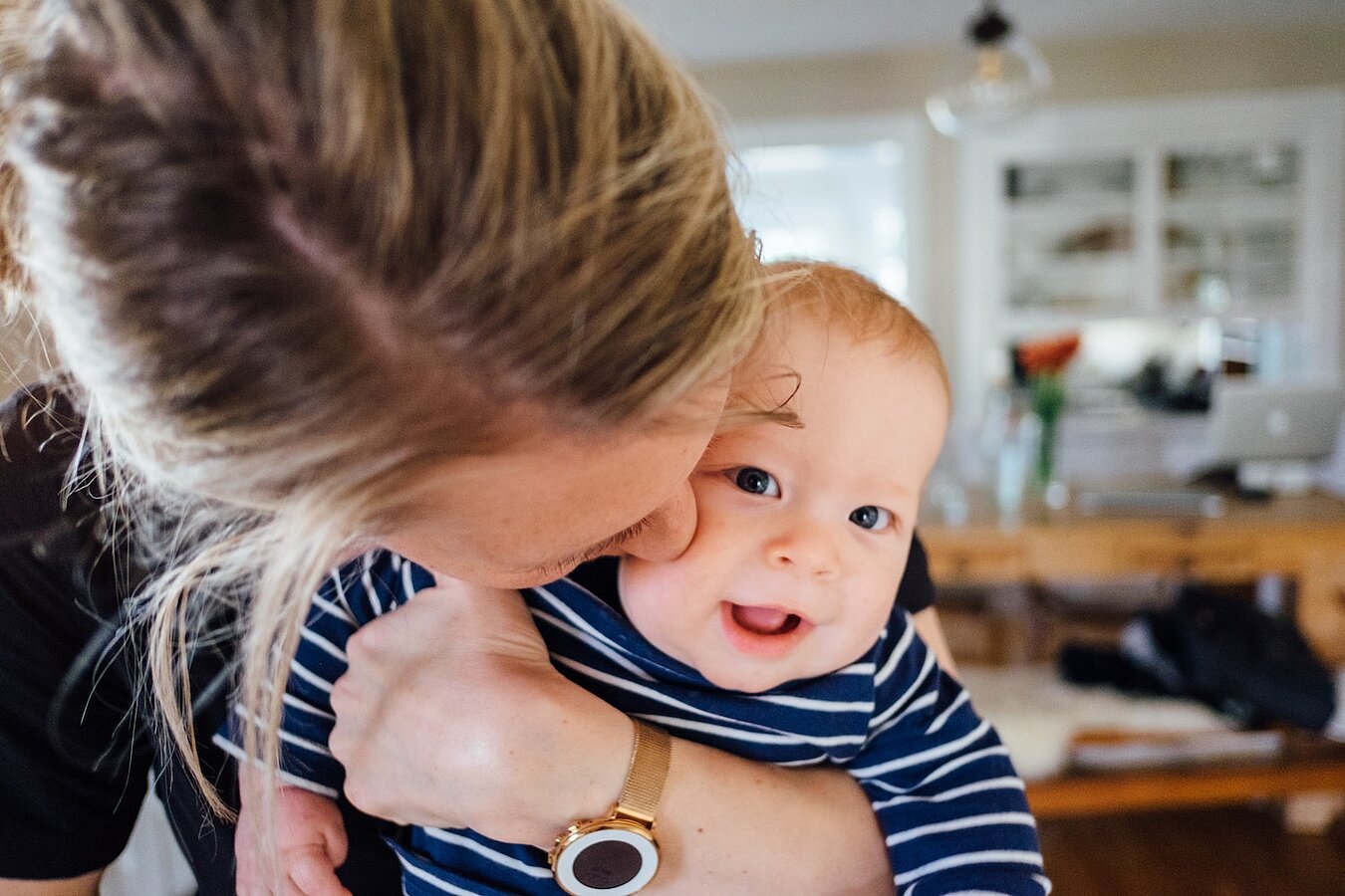 Frau hält Baby auf dem Arm, das in die Kamera schaut