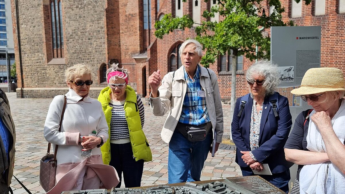 Menschen stehen vor einem Modell aus Bronze der Alt-Berliner Stadtteile