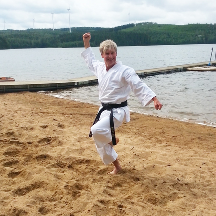 Ulrich Schulze macht im Karateanzug eine Karatepose am Strand