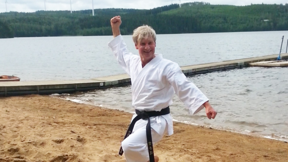 Ulrich Schulze macht im Karateanzug eine Karatepose am Strand