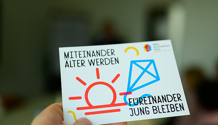 Karte mit Icon von einer Sonne und einem Spielzeug-Drachen mit der Aufschrift "Miteinander älter werden – füreinander jung bleiben"