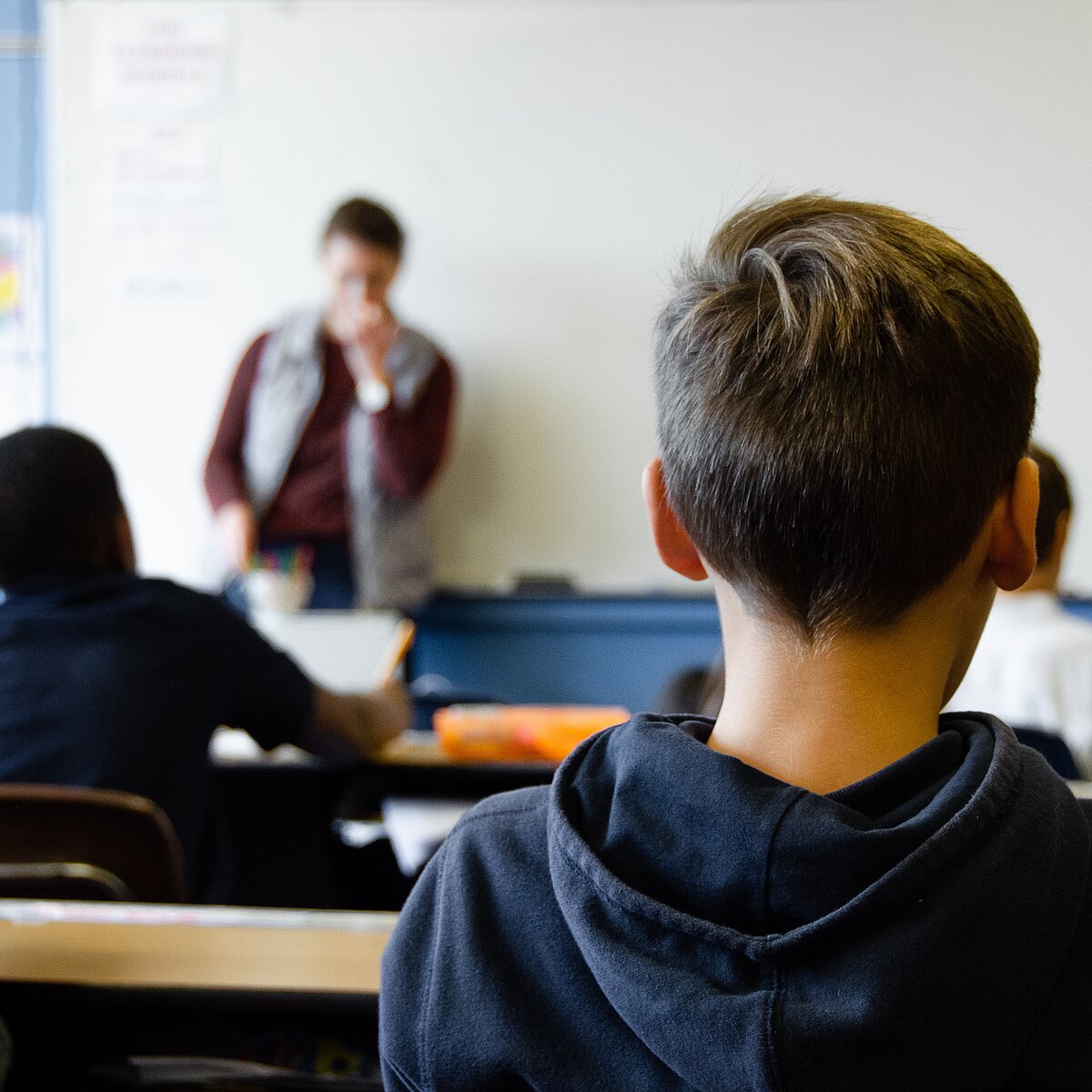 Kinder sitzen an Pulten in einem Klassenraum