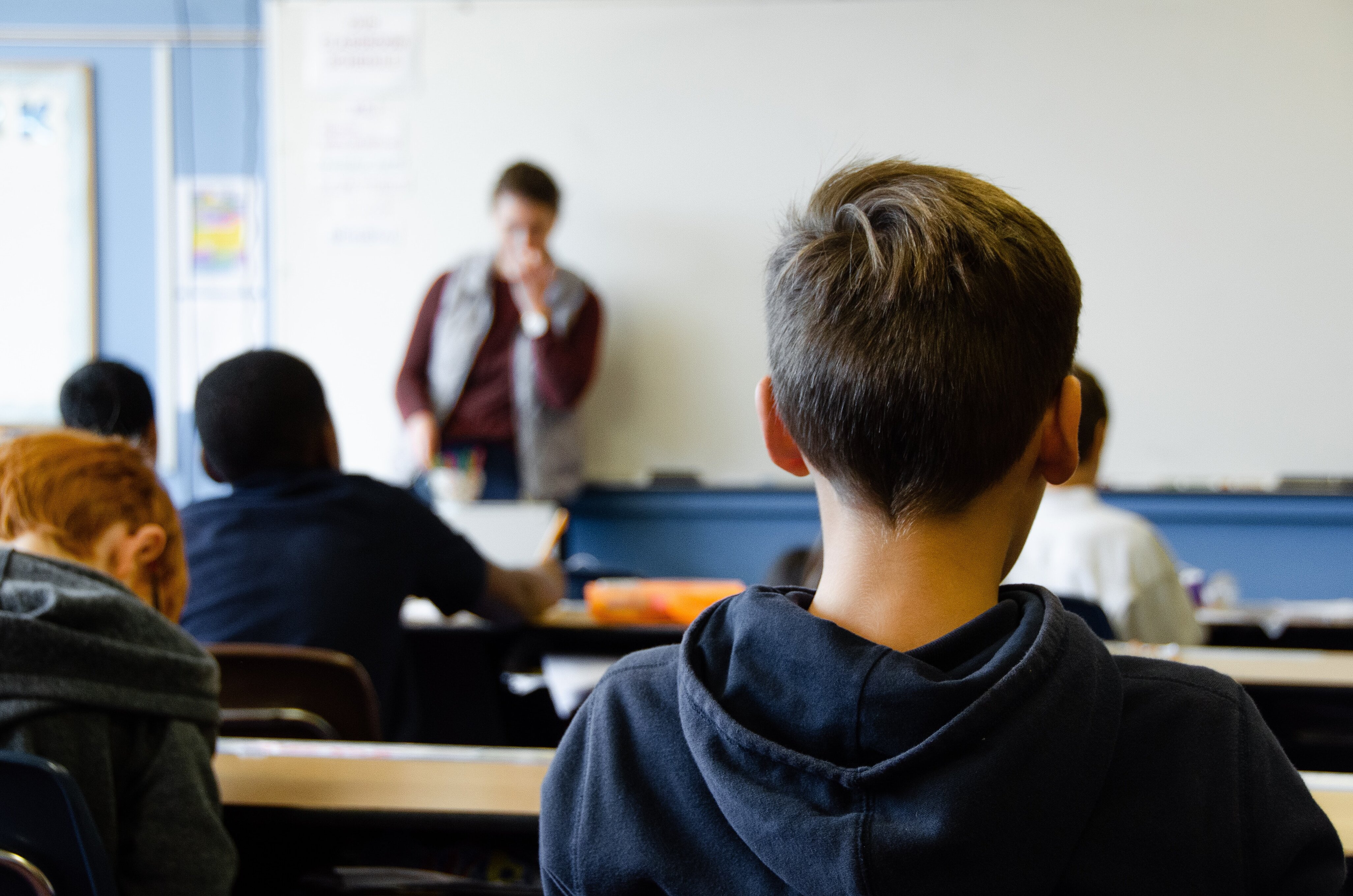 Kinder sitzen an Pulten in einem Klassenraum