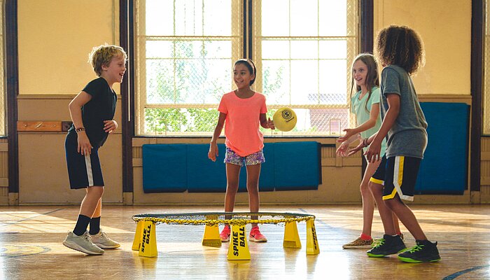 Vier Kinder spielen ein Ballspiel in einer Sporthalle