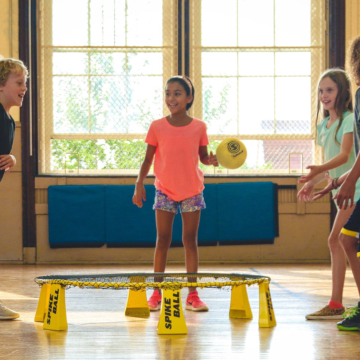 © Unsplash Vier Kinder spielen ein Ballspiel in einer Sporthalle