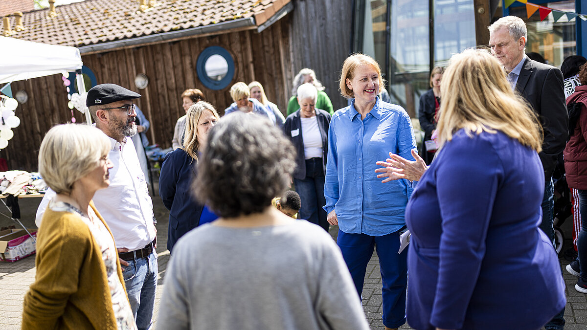 Ministerin Lisa Paus unterhält sich draußen mit verschiedenen Menschen. 