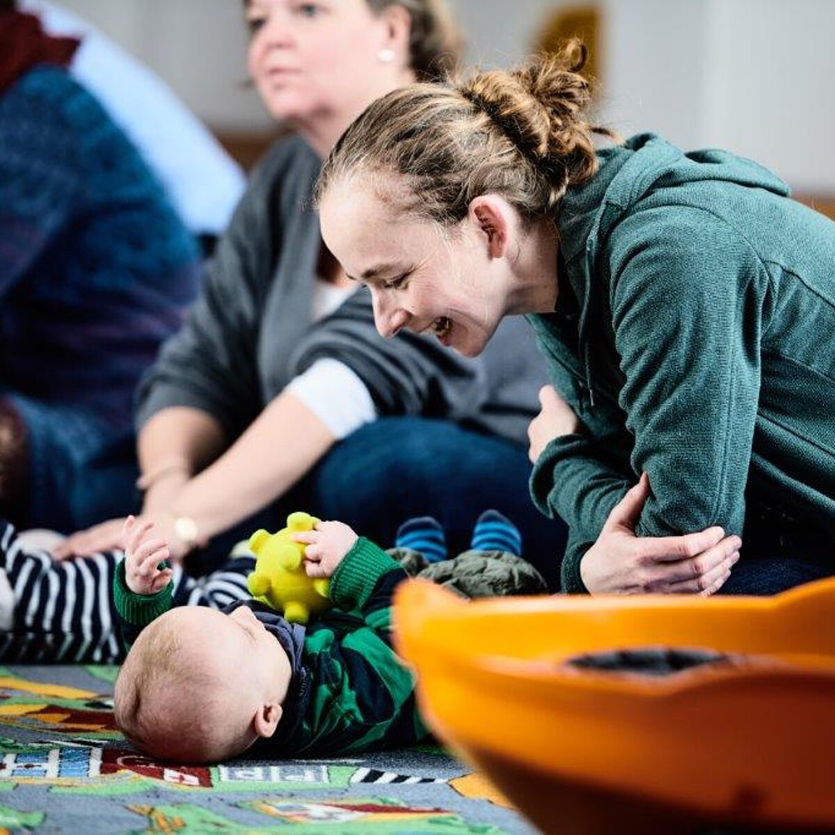 Eine Mutter spielt mit ihrem Baby auf dem Boden. 