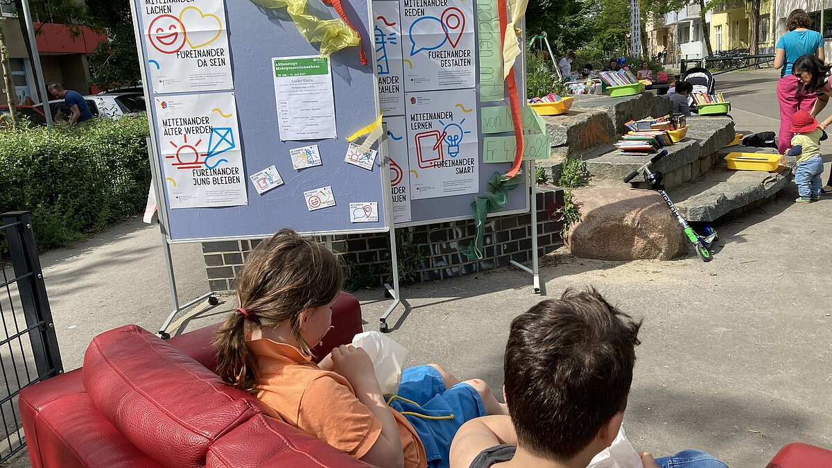 Zwei Metaplanwände stehen in einer Fußgängerzone, Bücher liegen auf einer Steintreppe aus, Kinder sitzen auf einem Sofa und lesen