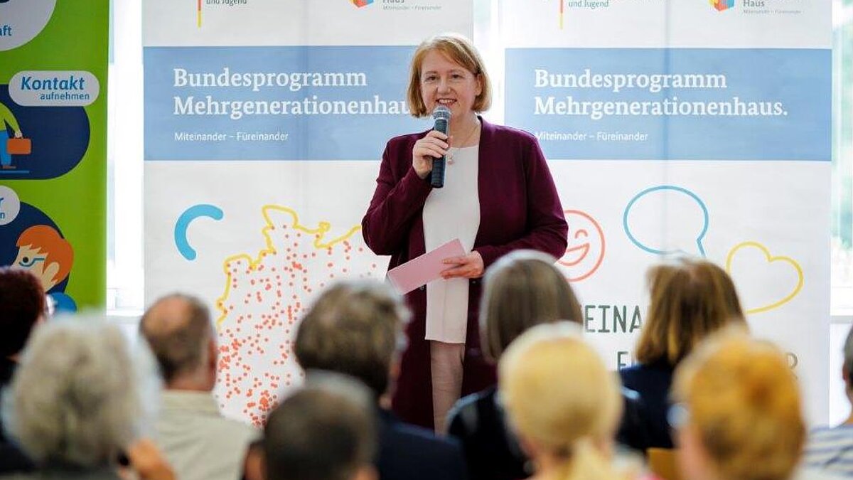 Bundesfamilienministerin Lisa Paus steht mit einem Mikrofon in der Hand vor einem Publikum