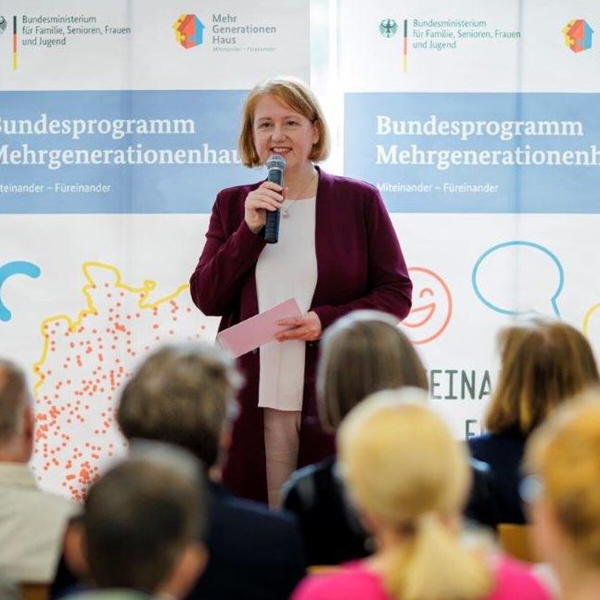 Bundesfamilienministerin Lisa Paus steht mit einem Mikrofon in der Hand vor einem Publikum