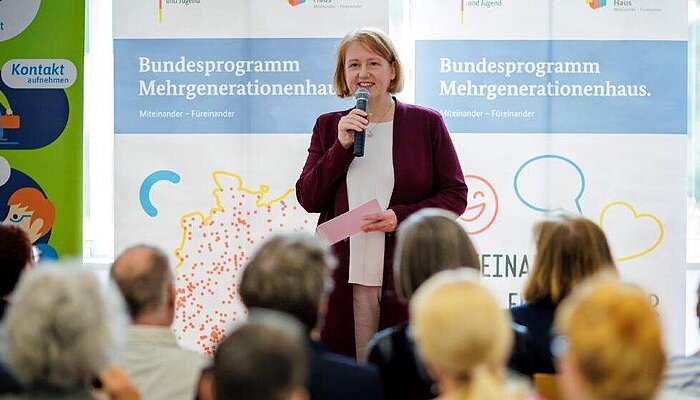 Bundesfamilienministerin Lisa Paus steht mit einem Mikrofon in der Hand vor einem Publikum