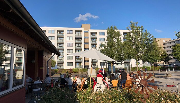 Tische und Stühle unter einen Sonnenschirm vor dem Mehrgenerationenhaus Grone