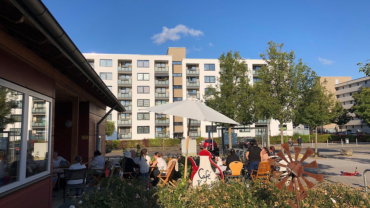 Tische und Stühle unter einen Sonnenschirm vor dem Mehrgenerationenhaus Grone