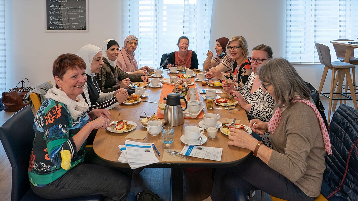 Mehrere Frauen sitzen an einem Tisch und frühstücken