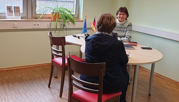 Zwei Frauen sitzen in einer Beratungssituation am Tisch.