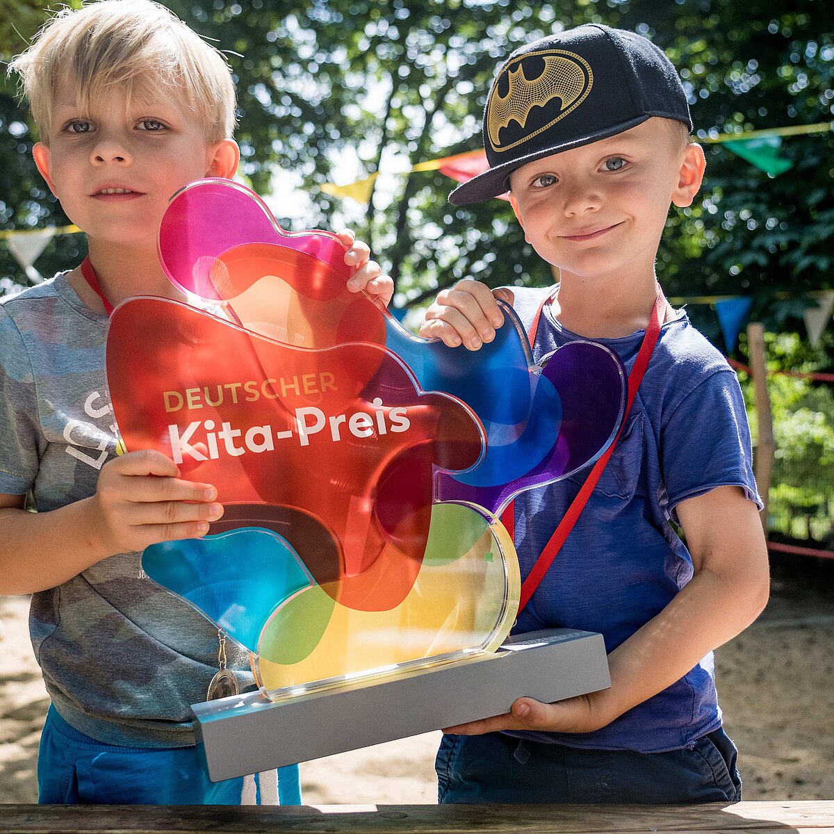 © DKJS/Franziska Schmitt Zwei Kinder halten die Trophäe des Deutschen Kita-Preises stolz in die Kamera