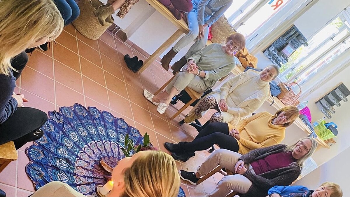 Mehrere Frauen sitzen in einer Runde und folgen einer Cacao-Zeremonie.