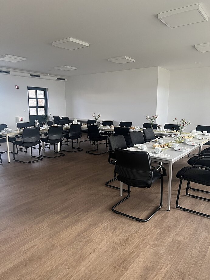 Großer Saal mit eingedeckter Kaffeetafel.