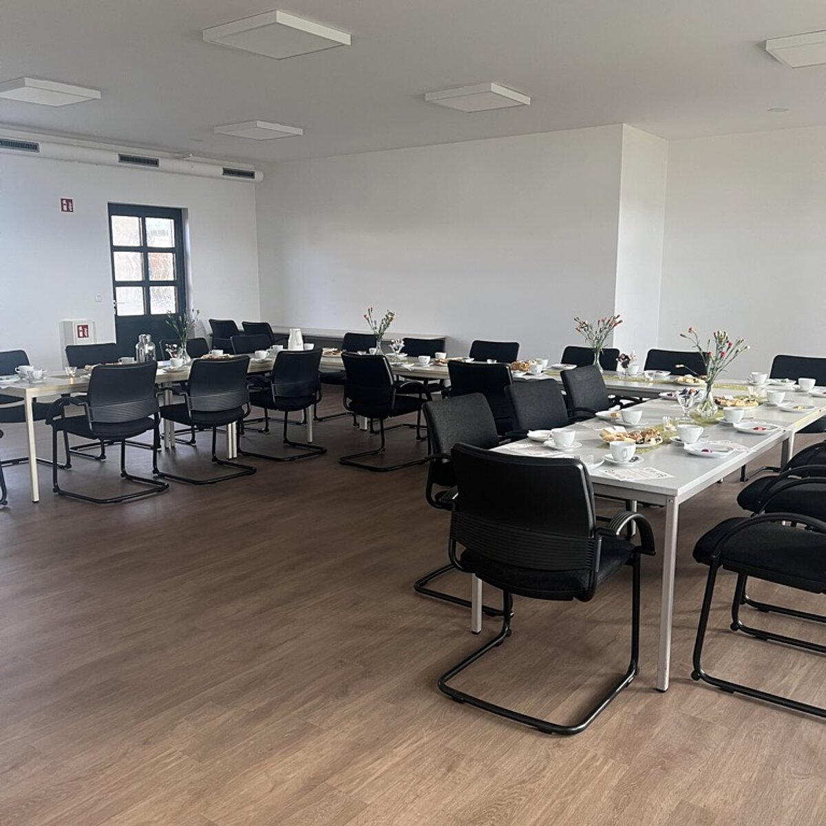 Großer Saal mit eingedeckter Kaffeetafel.