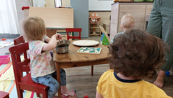 Drei Kinder spielen an einem Tisch