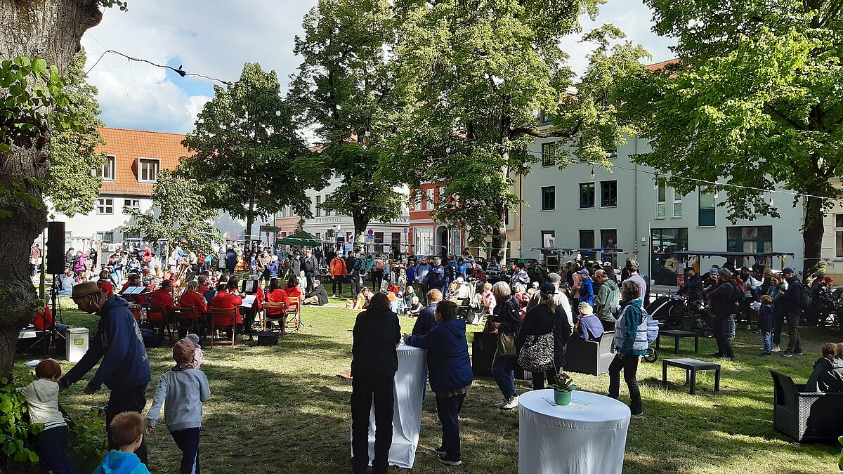 Ein voller Domvorplatz mit vielen Gästen und Ständen, das Blasorchester spielt