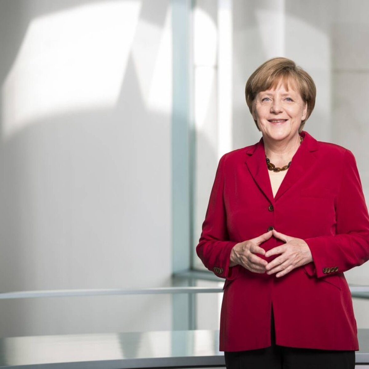 Porträtfoto von Angela Merkel, sie trägt einen roten Blazer.