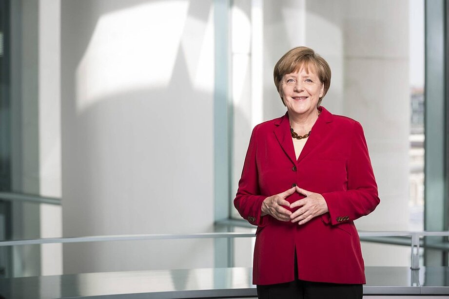 Porträtfoto von Angela Merkel, sie trägt einen roten Blazer.