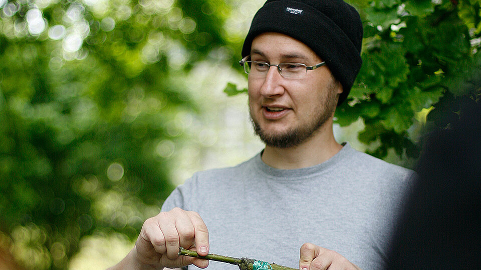 Volker Croy hält ein Werkzeug und hält einen Workshop