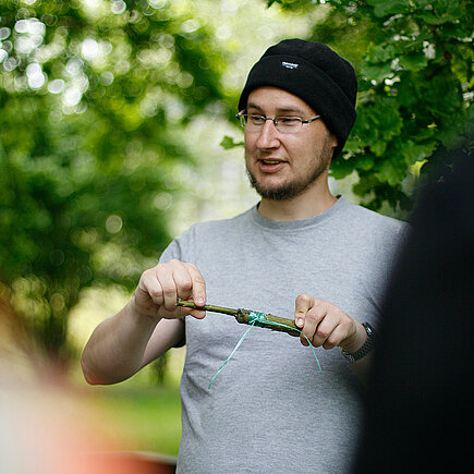 Volker Croy hält ein Werkzeug und hält einen Workshop