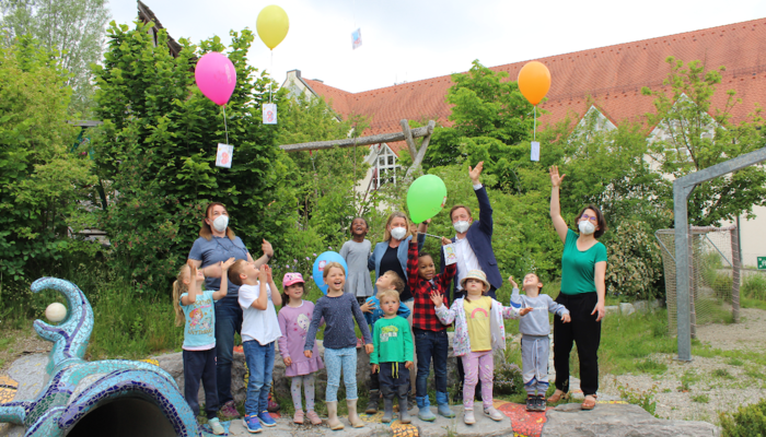 Neun Kinder und vier Frauen lassen Luftballons in die Luft steigen